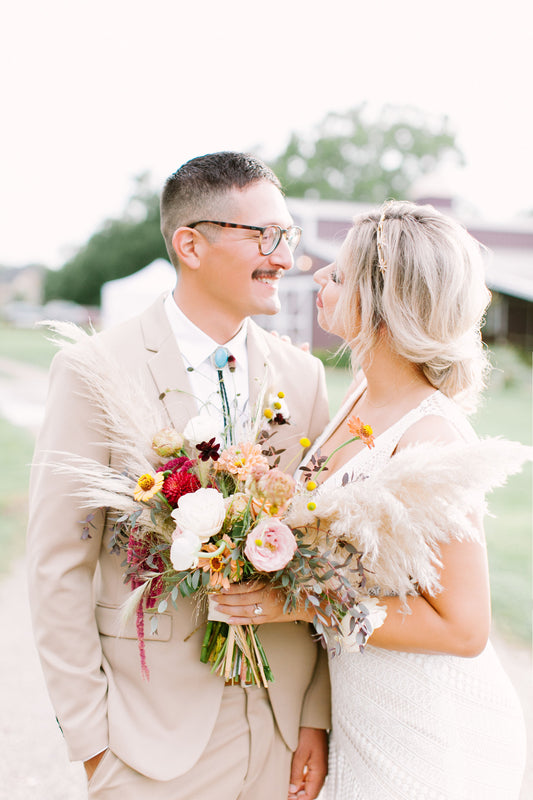 Young bride and groom making eye contact. Asymmetrical bouquet front and center.
