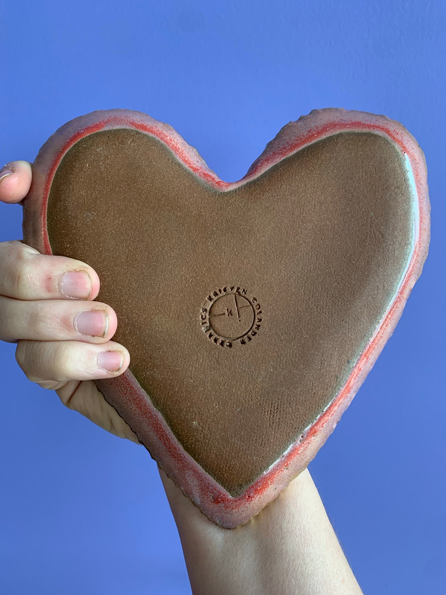 Hand holding Backside of heart shaped ring dish, grey on bottom