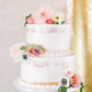 White layered wedding cake, edible flowers on top as design